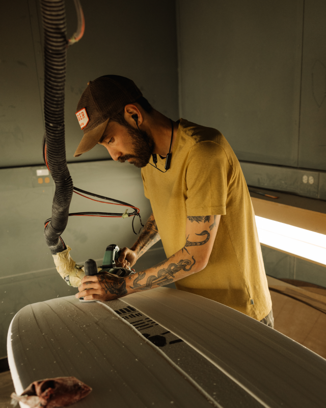 man carving surfboard