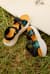 Teva sandals leaning against surfboard in grass