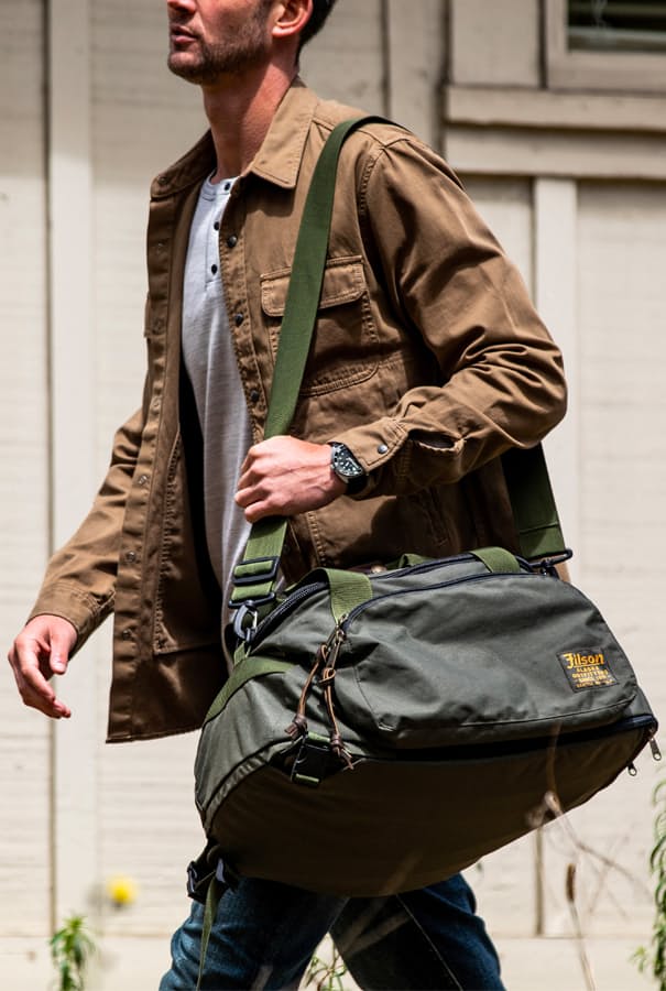 Man holding Filson duffle bag walking outdoors
