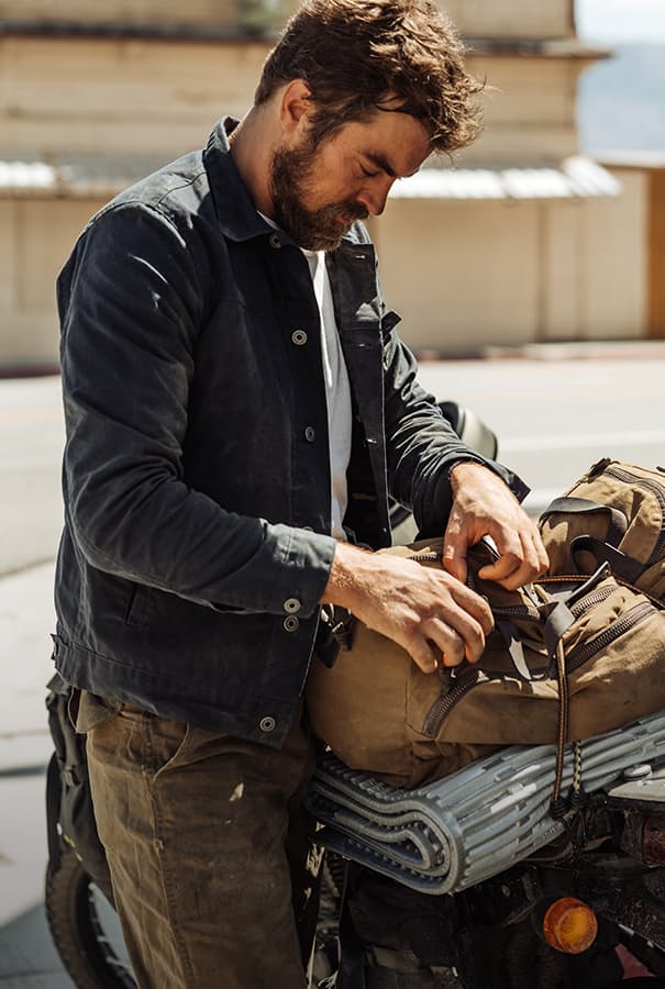 Model wearing waxed trucker jacket looking into bag