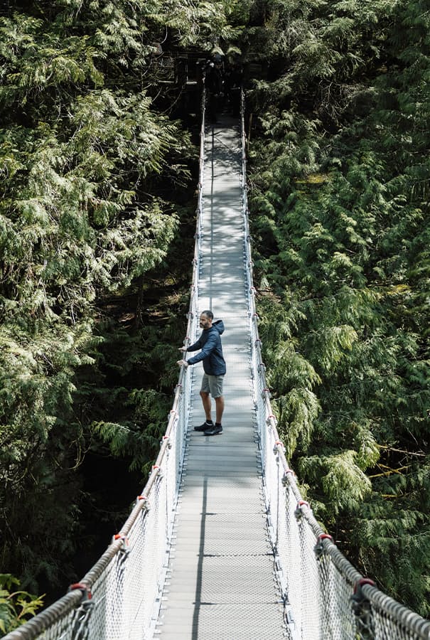 Man standing on bridge outside in wooded area