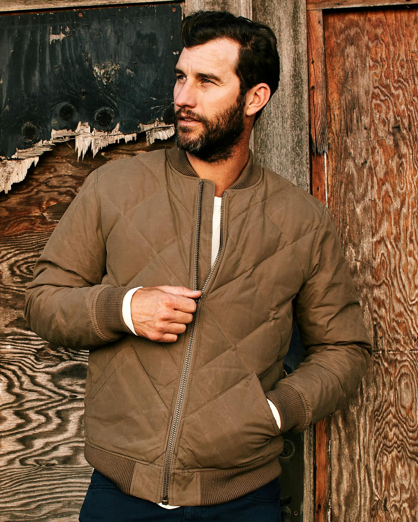 Man wearing jacket leaning against brick wall