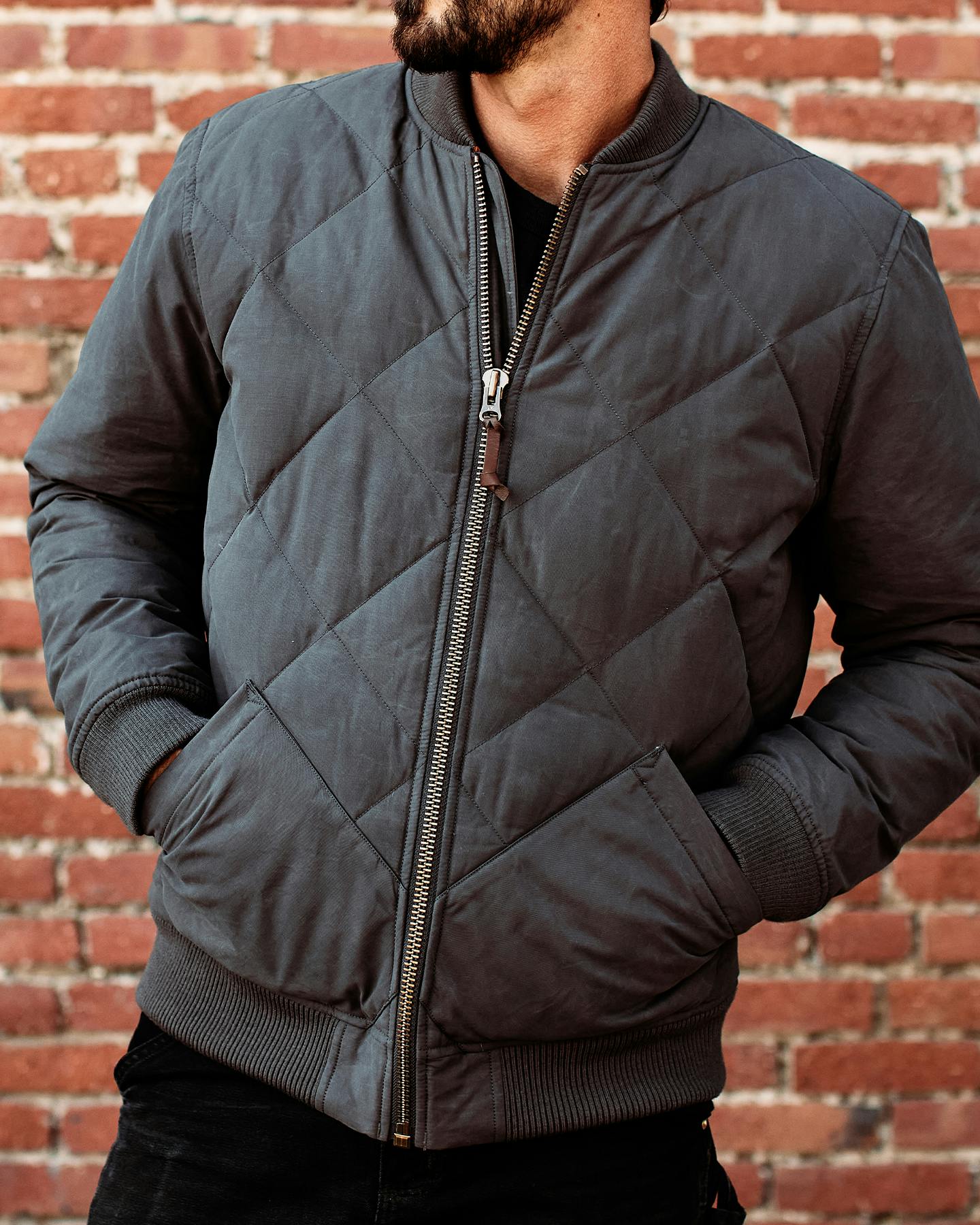 Man wearing jacket near brick wall
