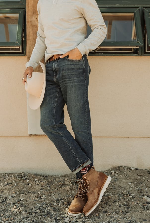 Man wearing jeans holding cowboy hat