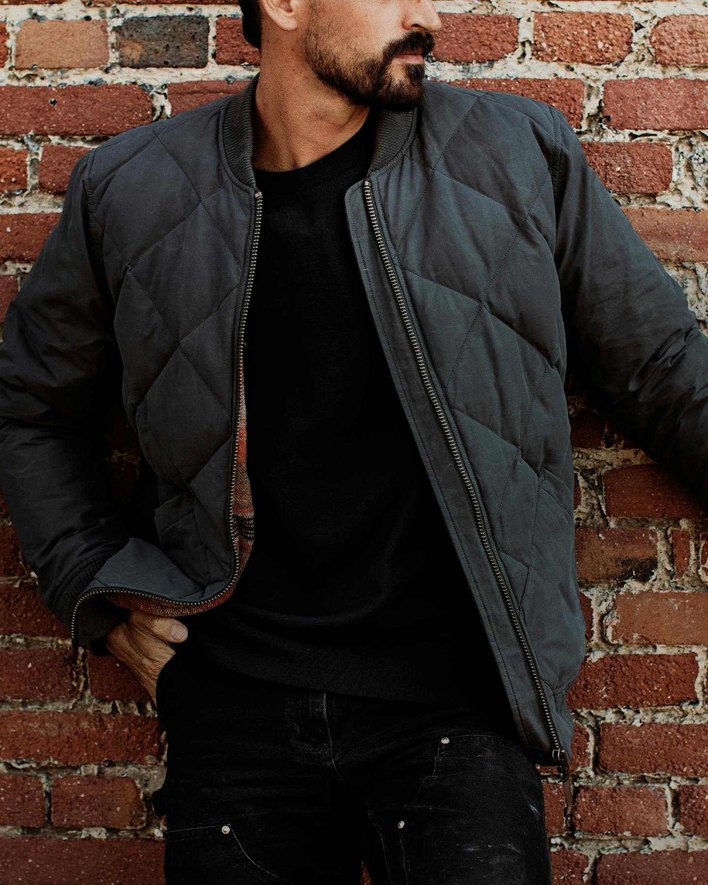 Man wearing jacket by brick wall