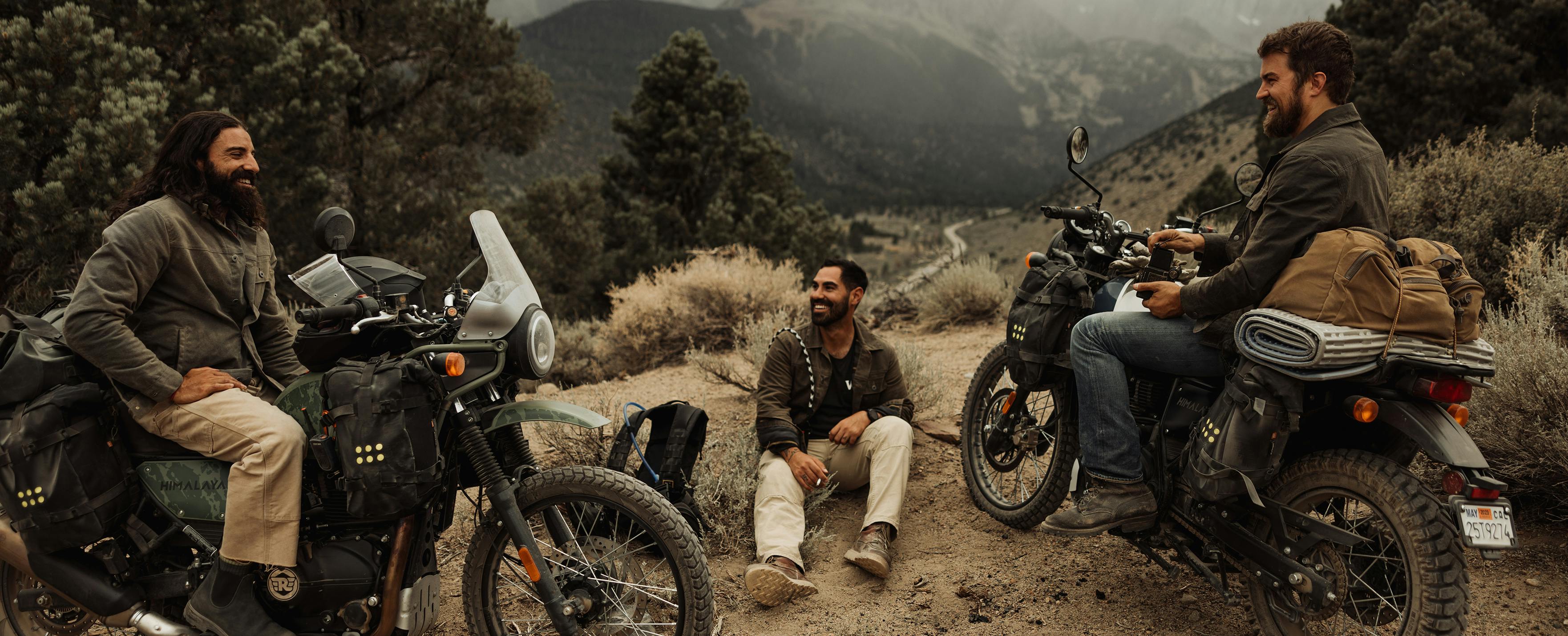 Men sitting in mountains on motorcycles chatting