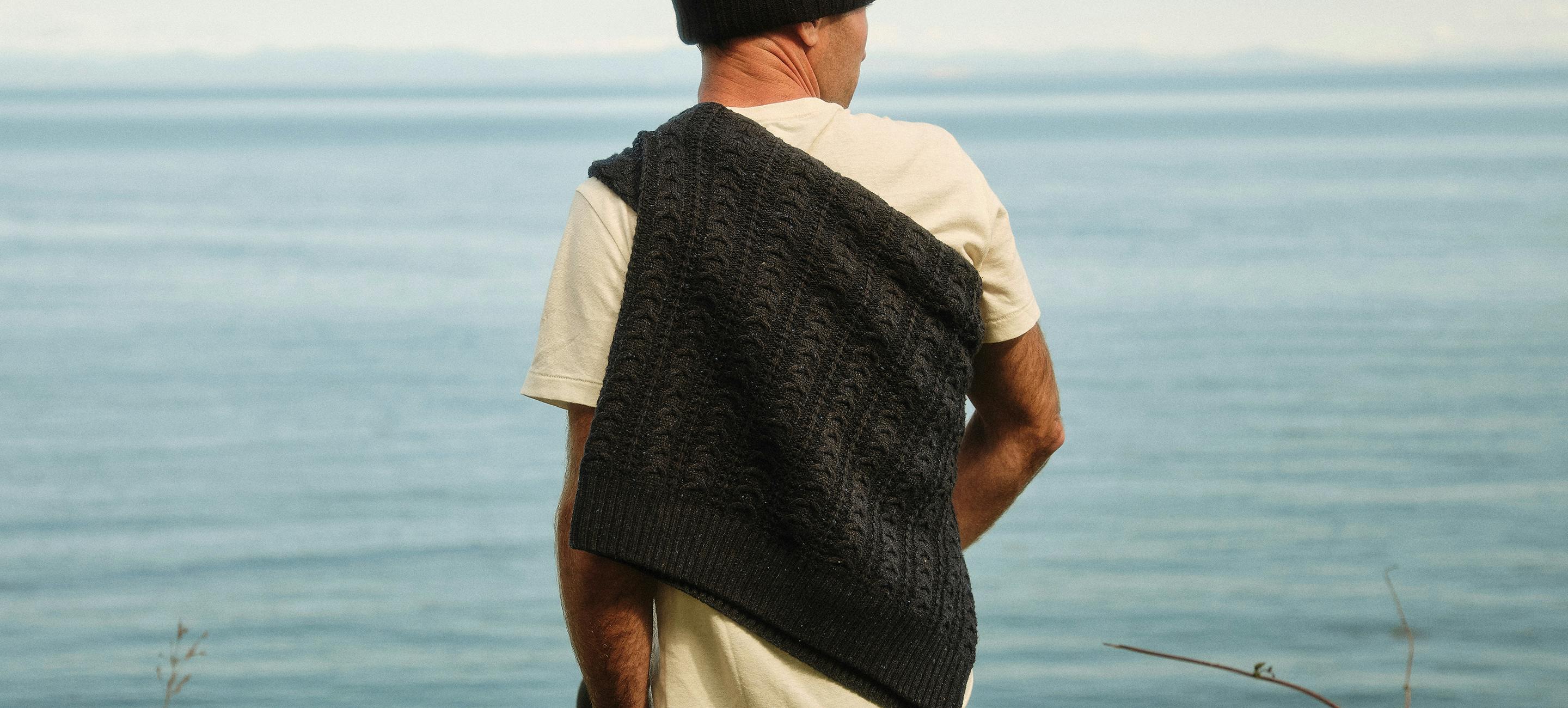 Man standing by water wearing seawool sweater on back